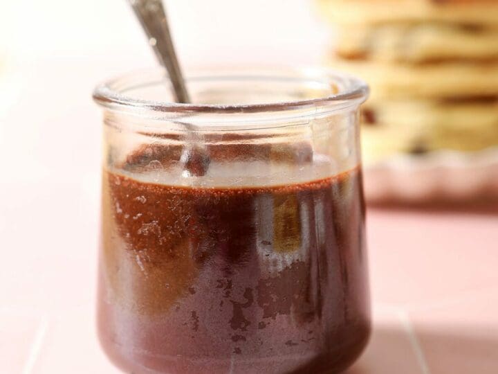 A spoon sits in a jar of hot fudge sauce