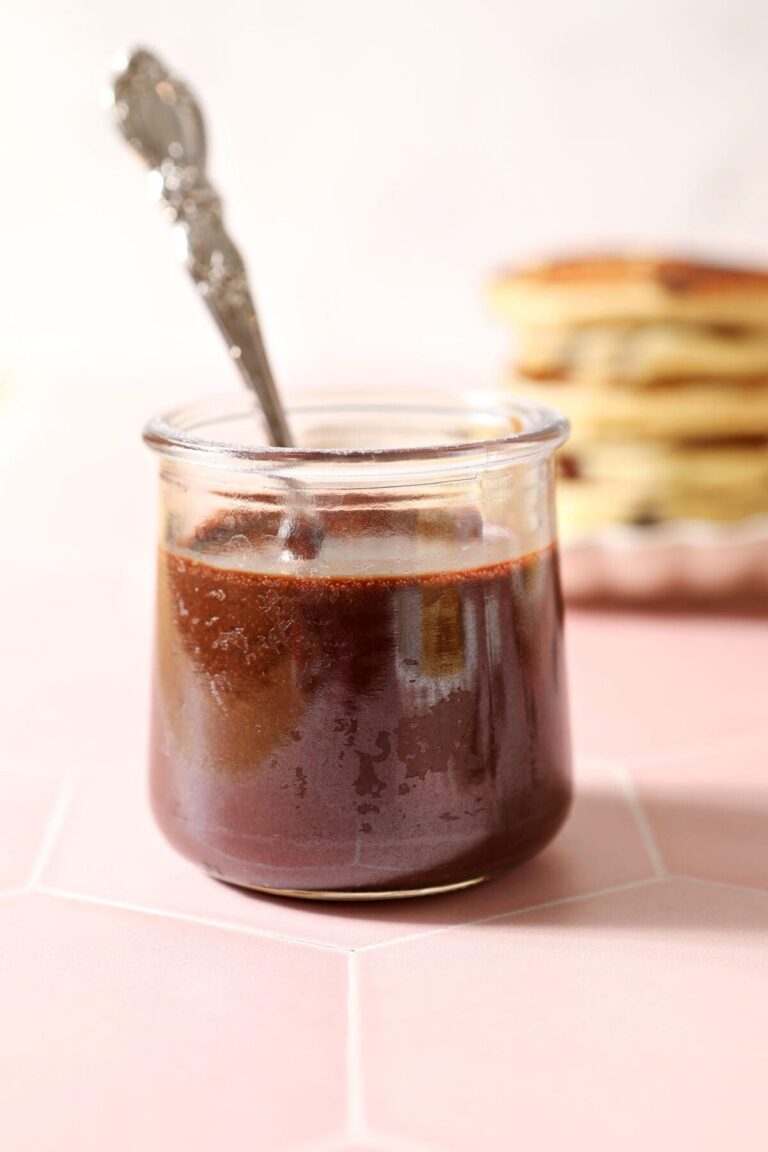 A spoon sits in a jar of hot fudge sauce