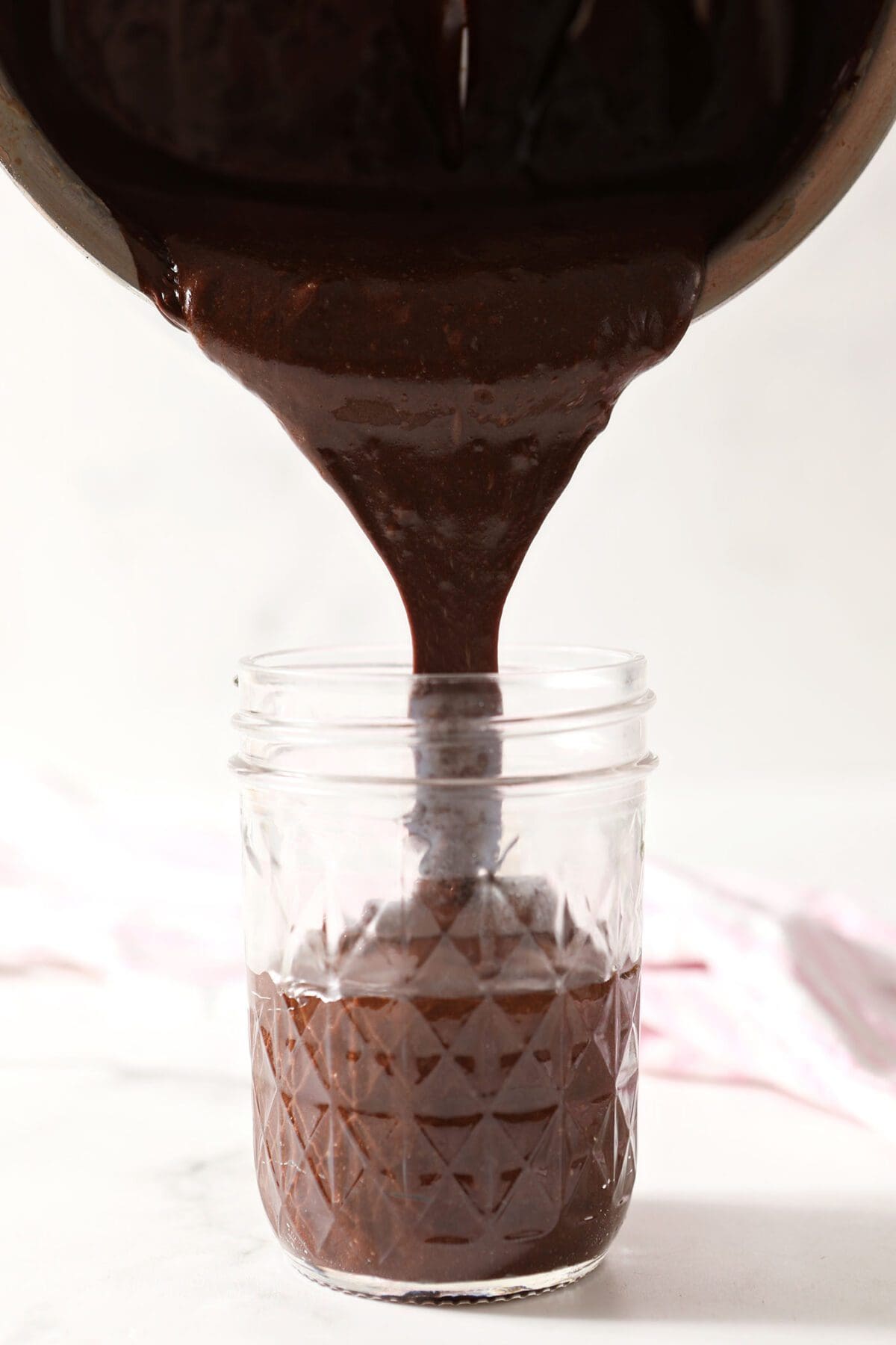Hot fudge sauce pours into a jar