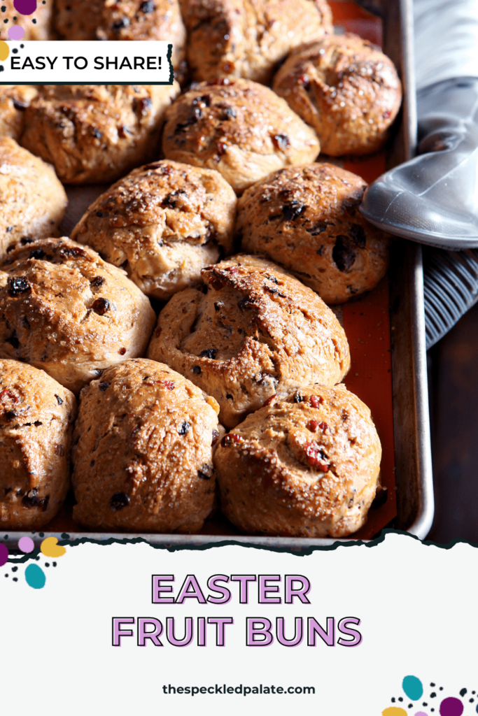 Freshly baked buns with dried fruit, being held while on a hot pan, straight out of the oven with the text Easter Fruit Buns