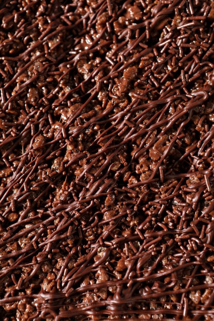 Close up of top of Chocolate Rice Krispie Treats drizzled with chocolate and chocolate sprinkles