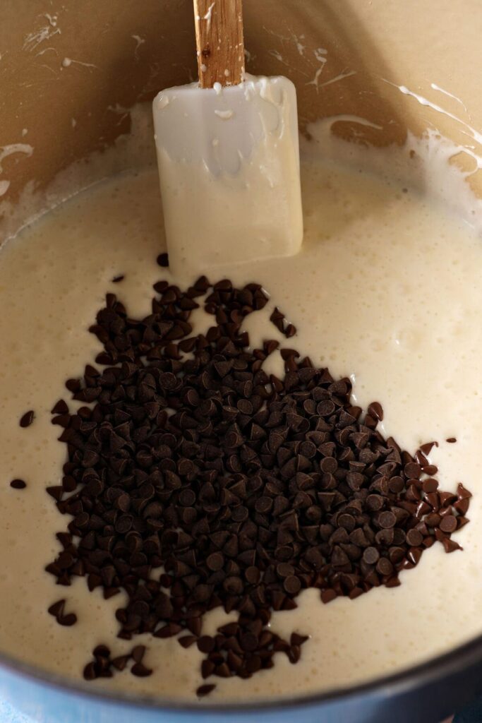 Mini chocolate chips added to melted butter and marshmallows in a dutch oven