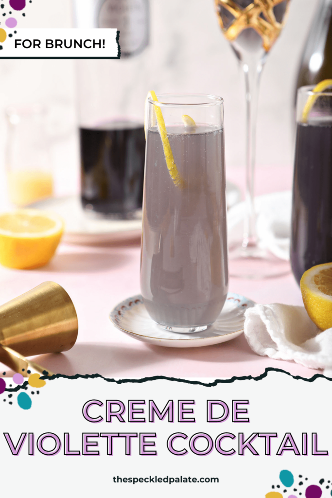 A champagne flute holds a purple drink garnished with a lemon twist with the text creme de violette cocktail