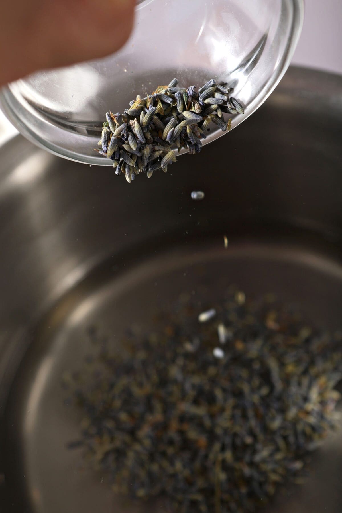 Lavender buds sprinkle into a saucepan with simple syrup