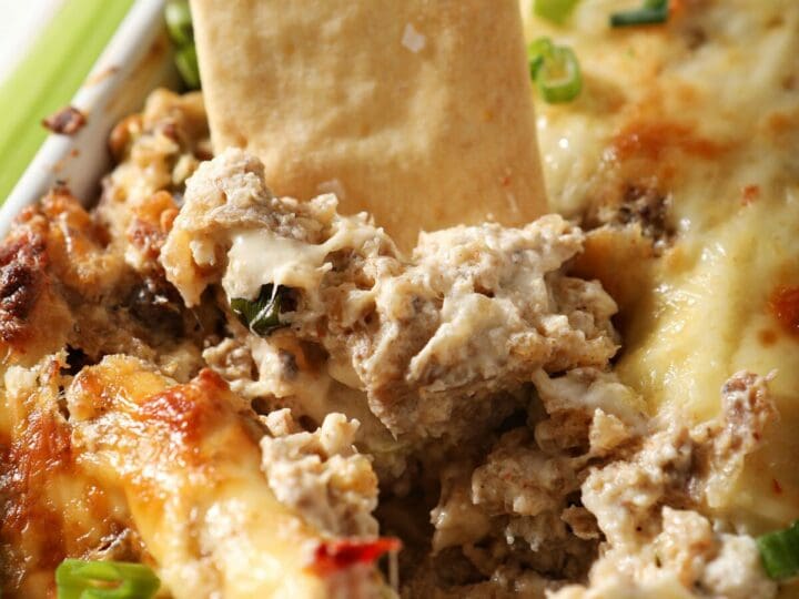 A pita chip is dunked into a container of hot boudin dip