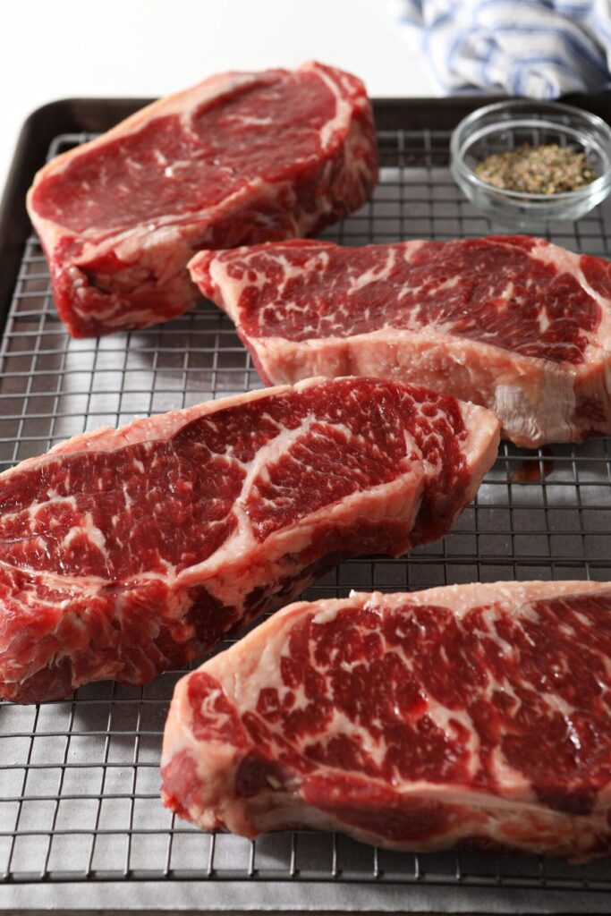 Steaks after seasoning with salt on a wire cooling rack