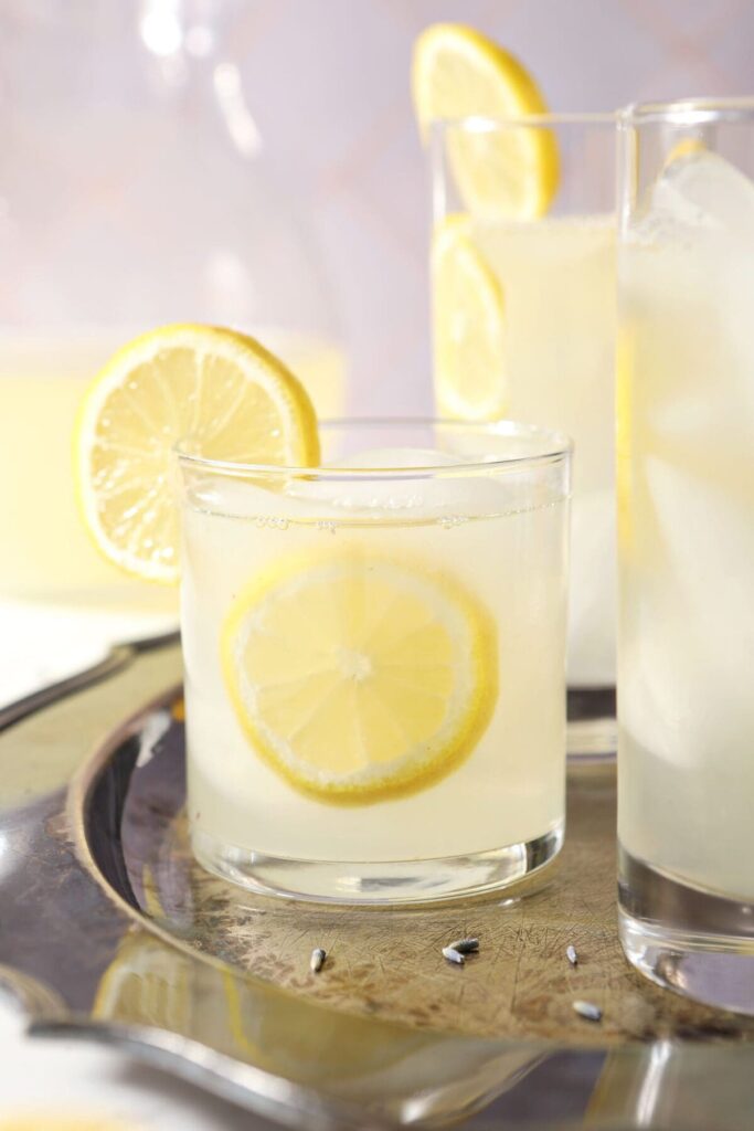 Close up of a short glass of lavender lemonade garnished with lemon wheels