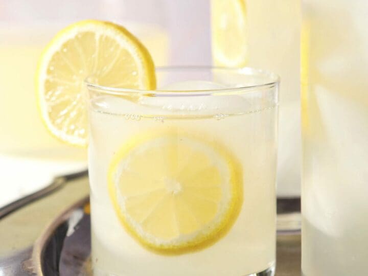 Close up of a short glass of lavender lemonade garnished with lemon wheels