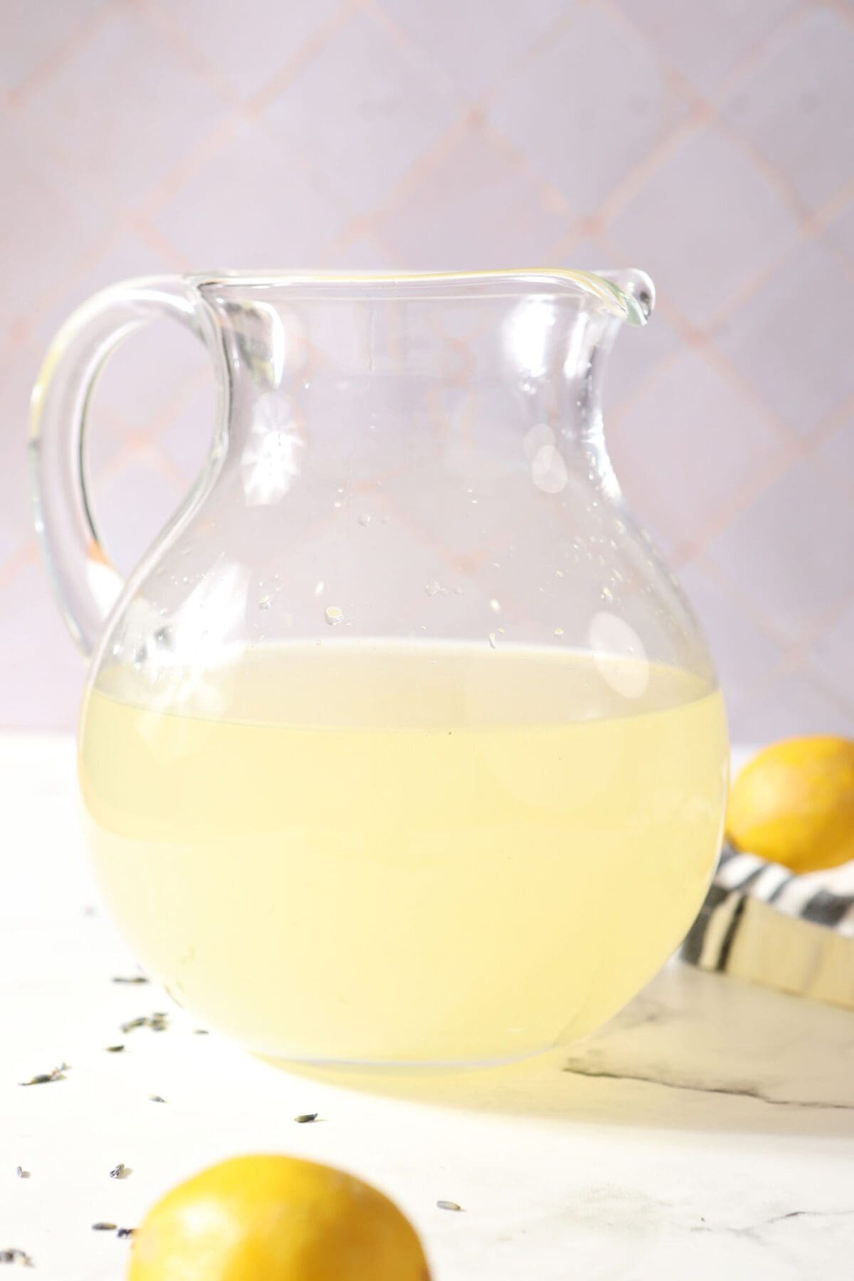 Homemade lavender lemonade in a pitcher on marble