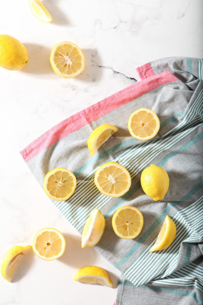 Sliced and halved lemons on a striped towel on marble