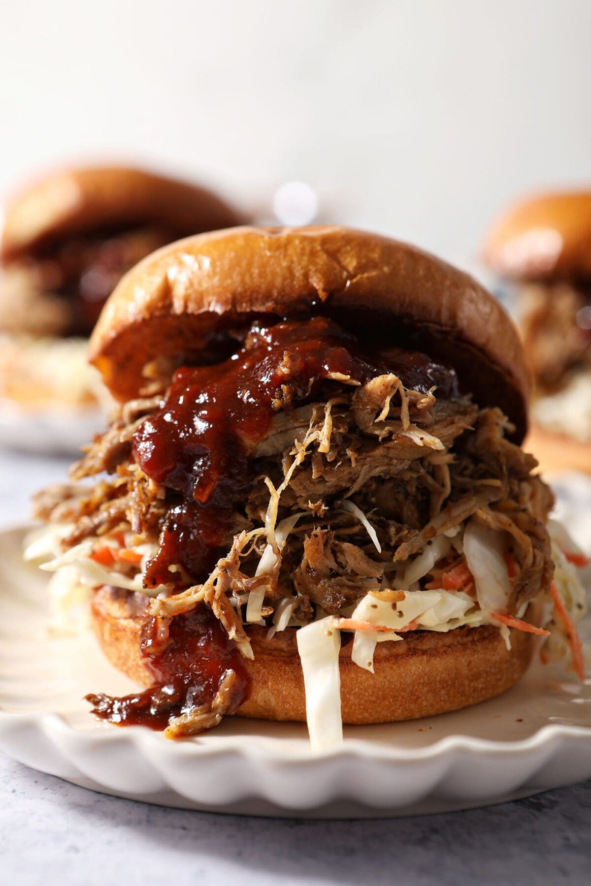 Close up of a pulled pork sandwich drizzled with BBQ sauce