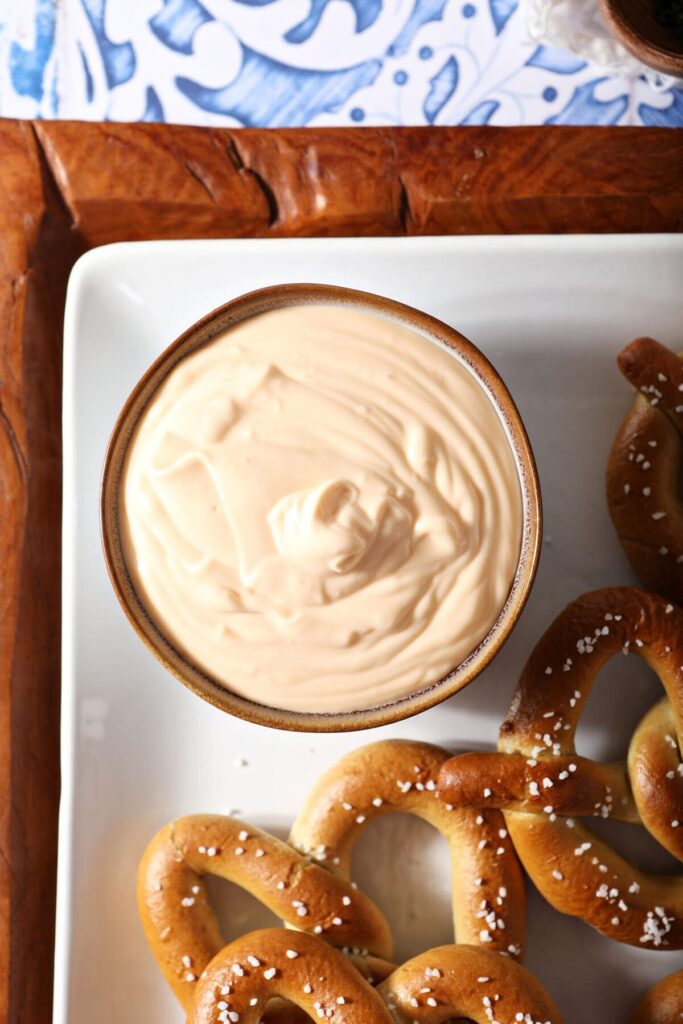 Cheese dip in a bowl surrounded by soft pretzels