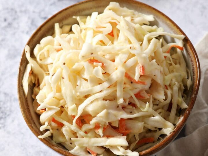 A bowl of coleslaw next to a bowl of baked beans