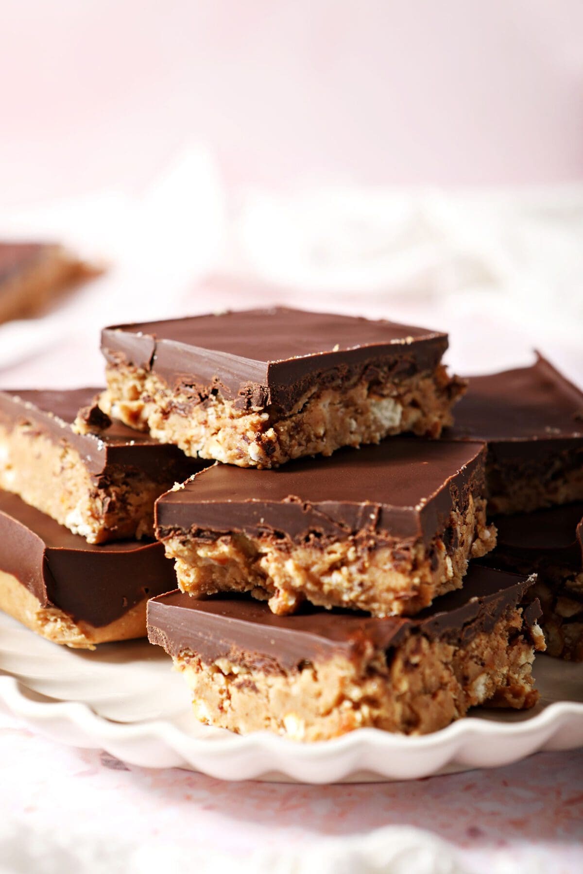 A scalloped plate holds a stack of Chocolate Peanut Butter Bars