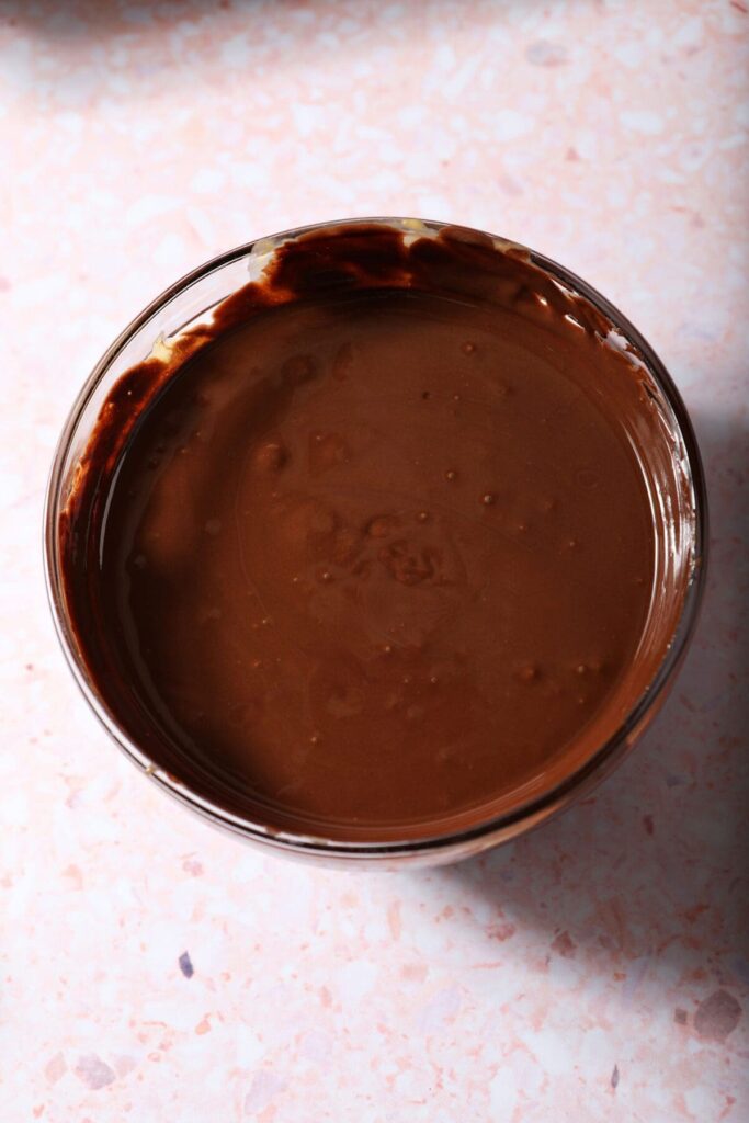 Melted chocolate peanut butter in a bowl on a pink surface