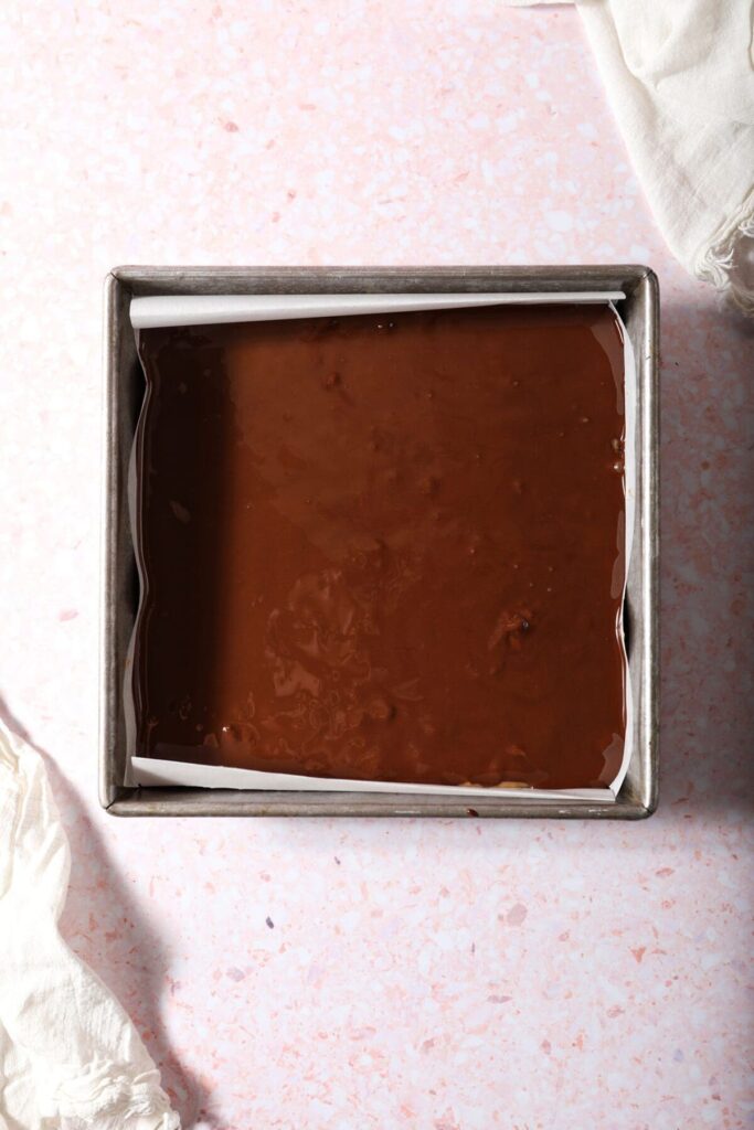 Hot chocolate coats the top of peanut butter bars in a square pan