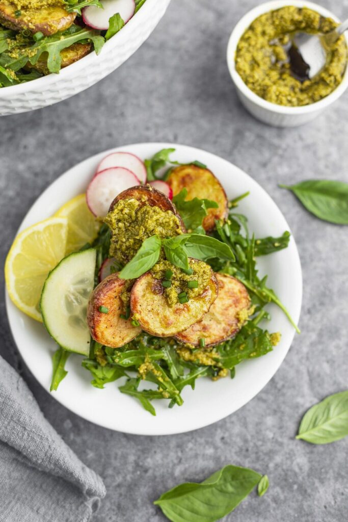 Overhead of an individual plate of roasted potatoes on top of an arugula salad