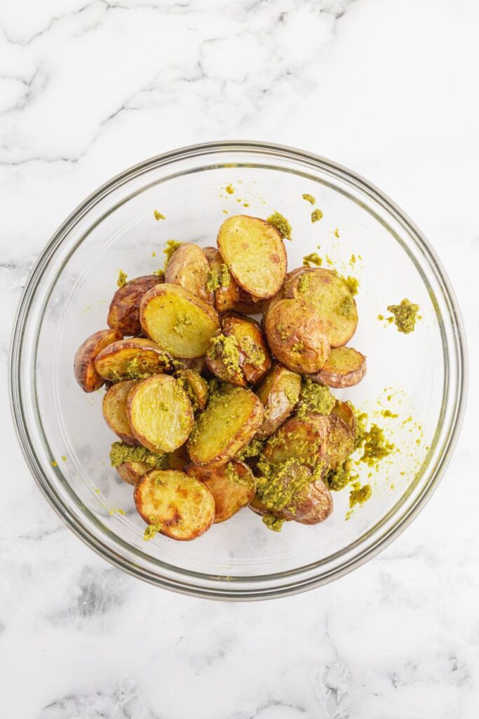 Roasted potatoes tossed in a bowl with pesto