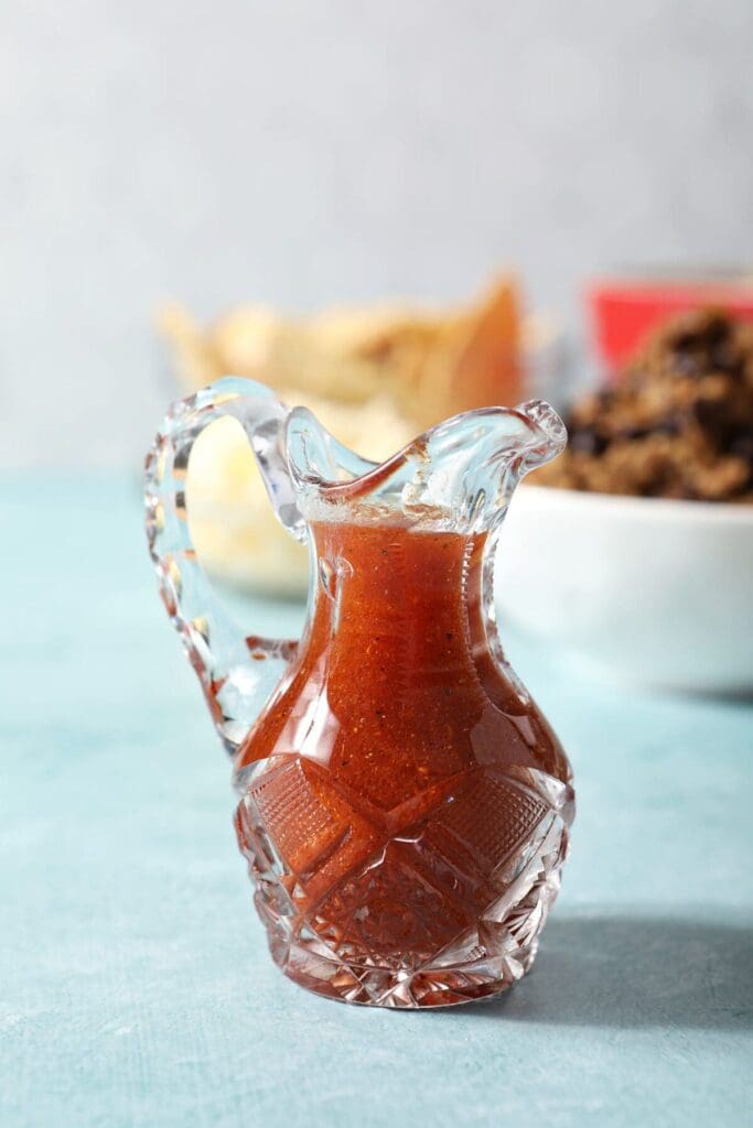 A small glass container holds homemade Catalina dressing beside salad ingredients