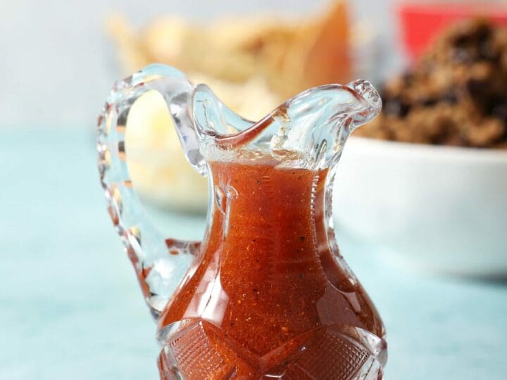 A small glass container holds homemade Catalina dressing beside salad ingredients