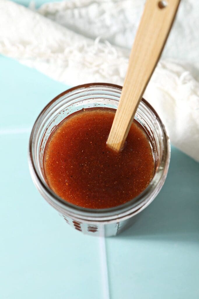 Closeup overhead of a mason jar of homemade Catalina dressing with a wooden spoon inside