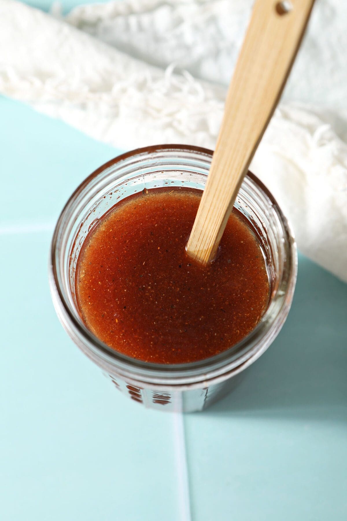 Closeup overhead of a mason jar of homemade Catalina dressing with a wooden spoon inside