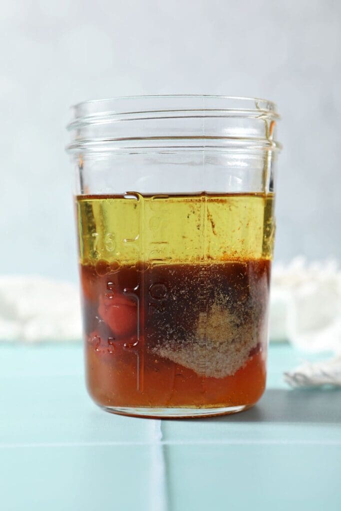 Ingredients to make Catalina dressing in a mason jar on a turquoise tile surface before mixing