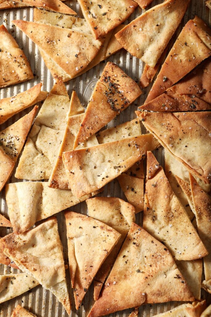 Close up of golden brown baked pita chips on a sheet pan