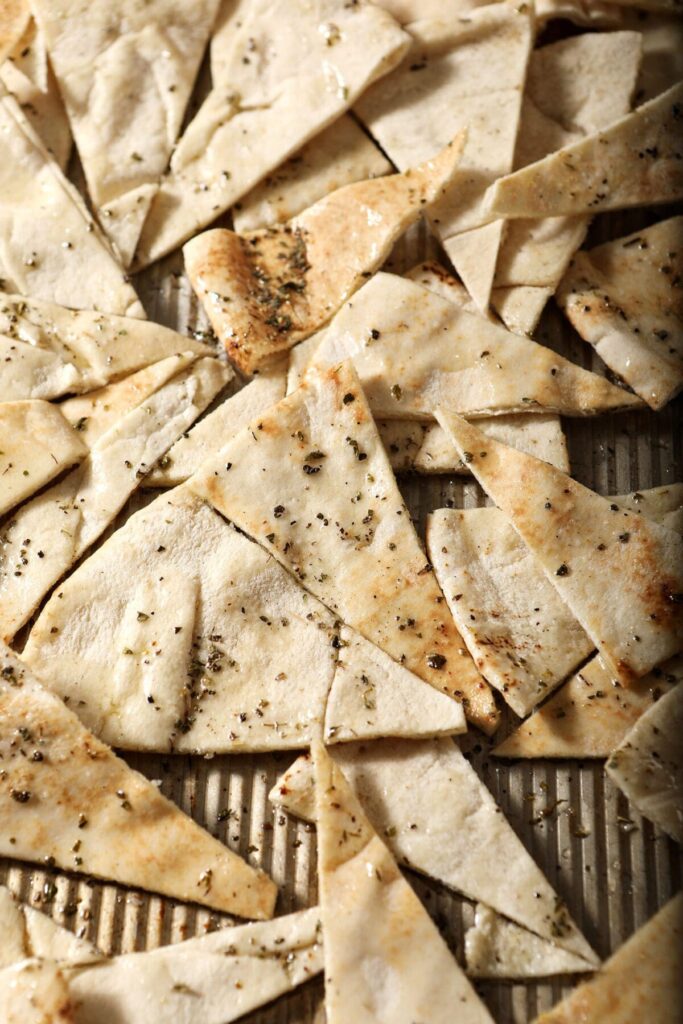 Seasoned pita triangles on a sheet pan before baking