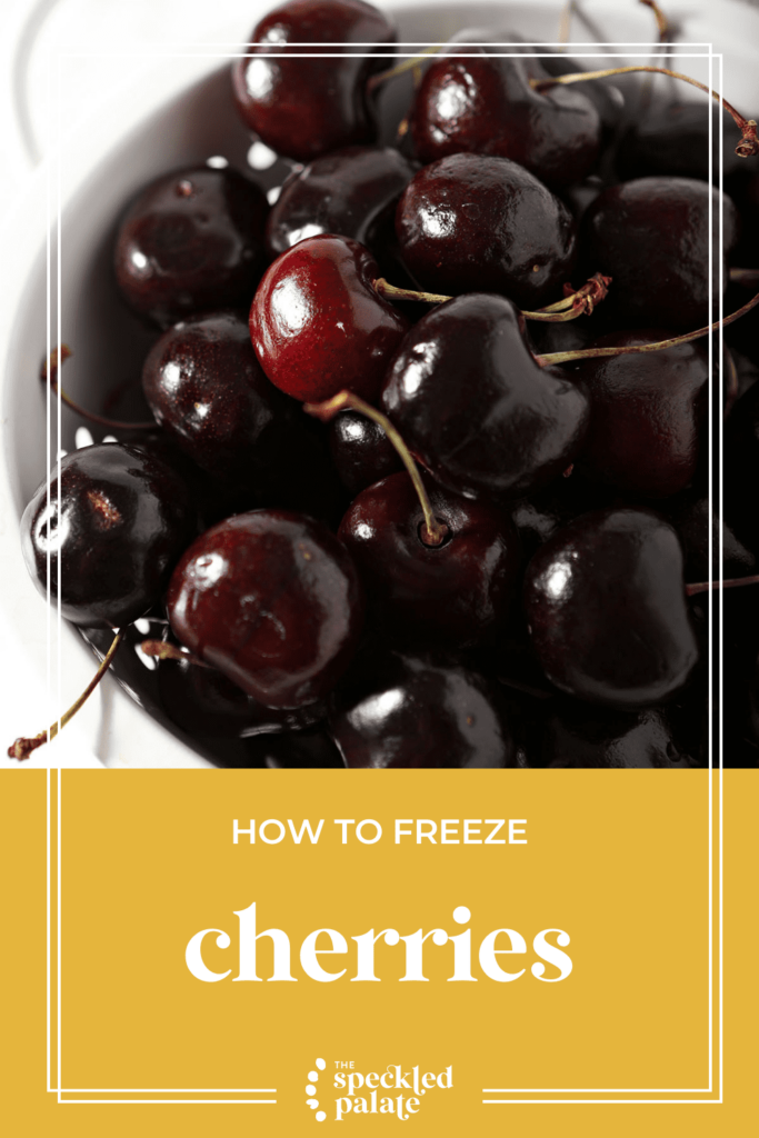 A white colander holds whole cherries with the text how to freeze cherries