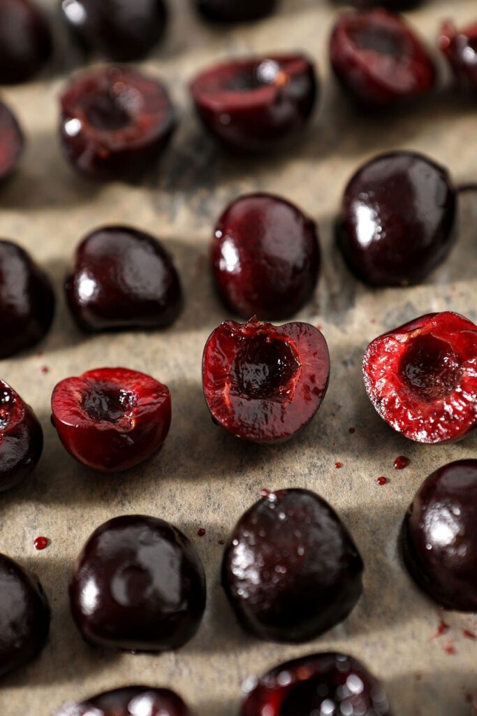 Close up of halved cherries on a sheet pan before freezing