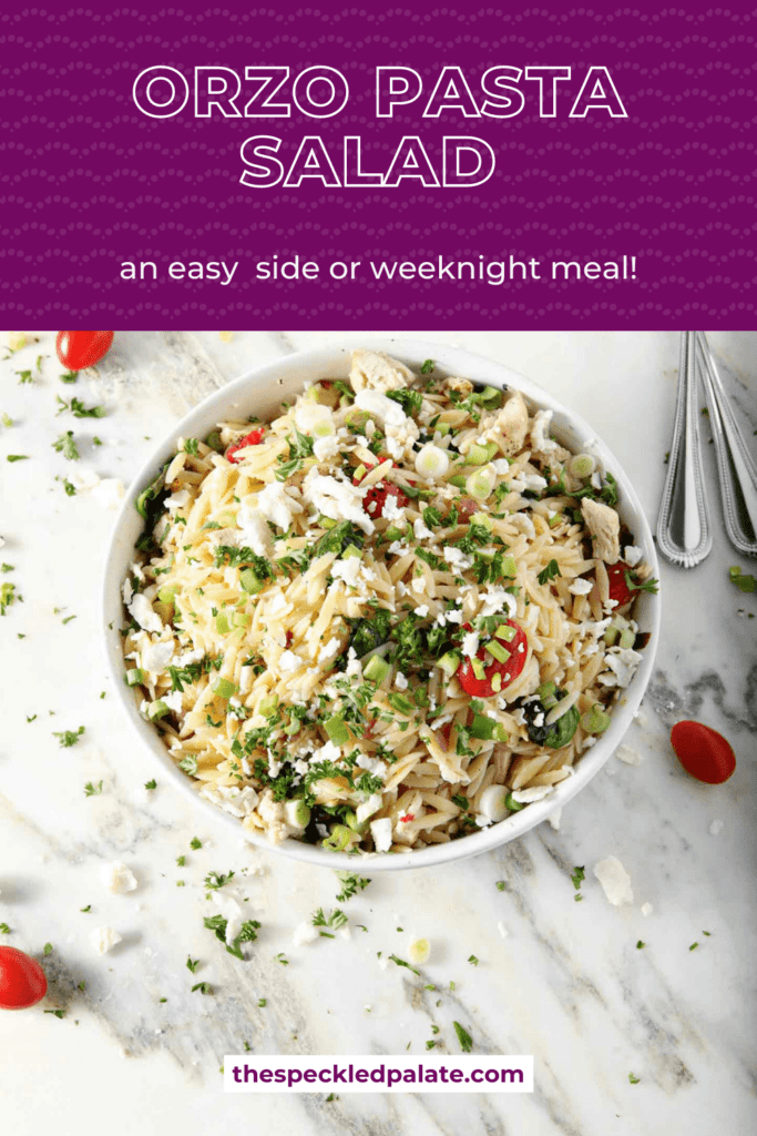 Overhead of a bowl of Greek Orzo Pasta Salad on marble, surrounded by tomatoes, chopped parsley, lemon and red onion with the text orzo pasta salad an easy side or weeknight meal