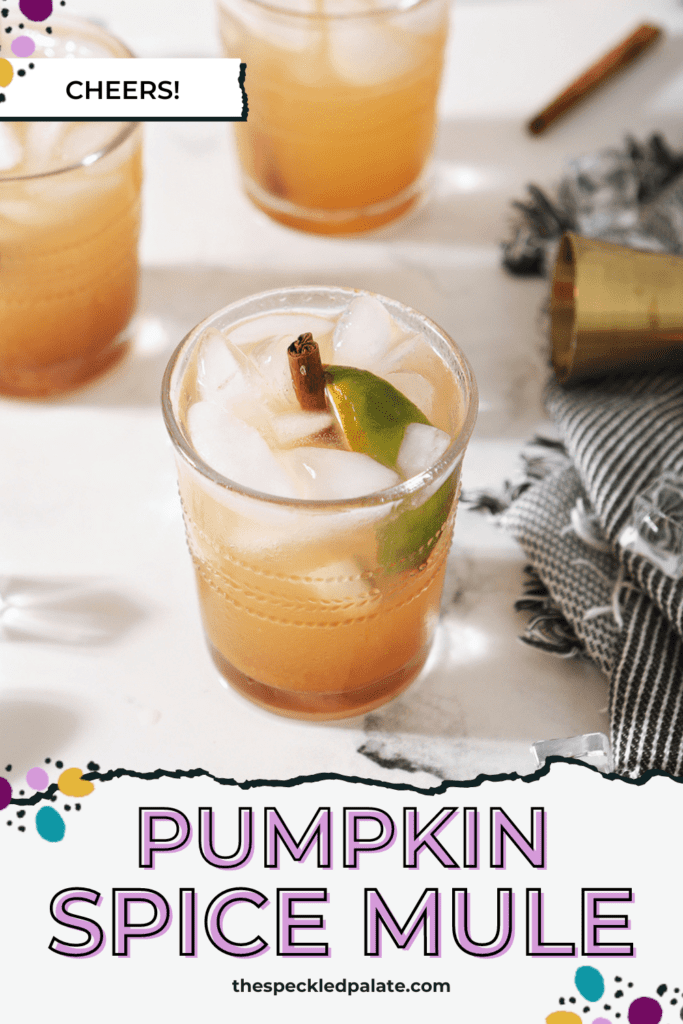 Three pumpkin spice moscow mules, garnished with cinnamon sticks and lime wedges, surrounded by limes, pumpkin and a jigger on marble with the text pumpkin spice mule