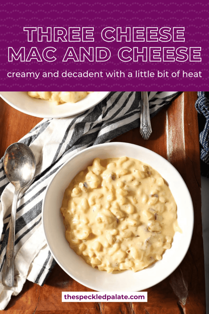 Two bowls of macaroni and cheese in white bowls next to spoons with the text three cheese Mac and cheese creamy and decadent with a little bit of heat