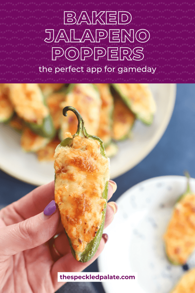 A woman holds a golden brown cheesy jalapeño popper in hand above a large serving platter with the text baked jalapeno poppers the perfect app for gameday