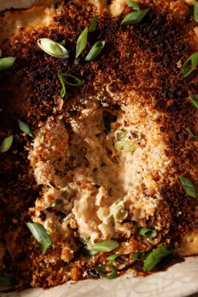 Close up of crawfish dip, topped with browned panko and sliced green onions