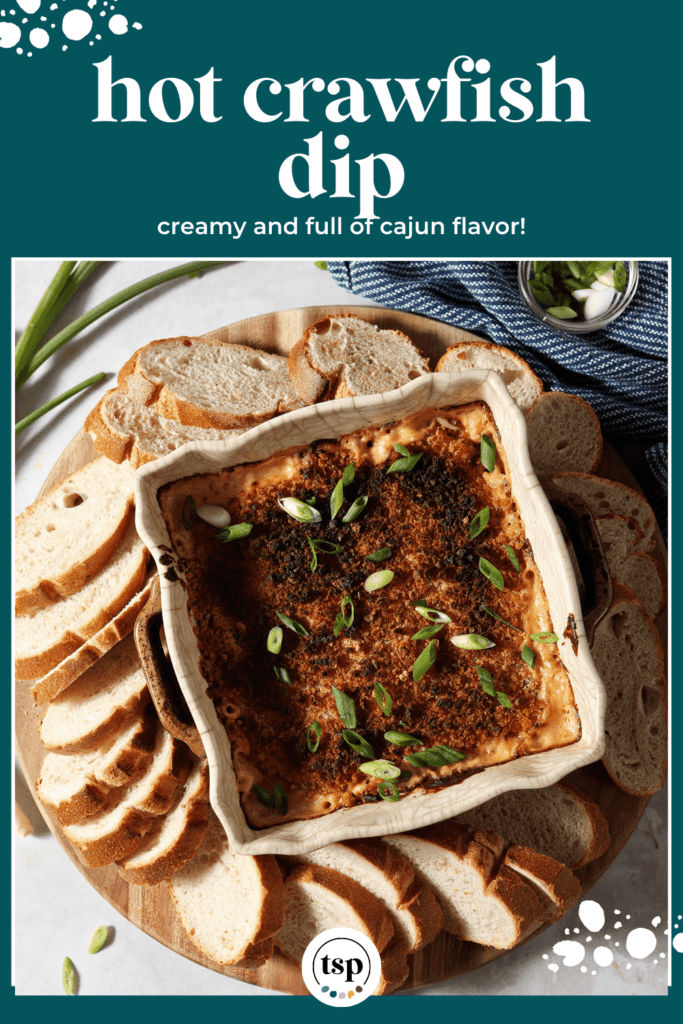 Crawfish dip in a casserole dish surrounded by baguette slices and garnished with green onion with the text Hot Crawfish Dip creamy and full of cajun flavor