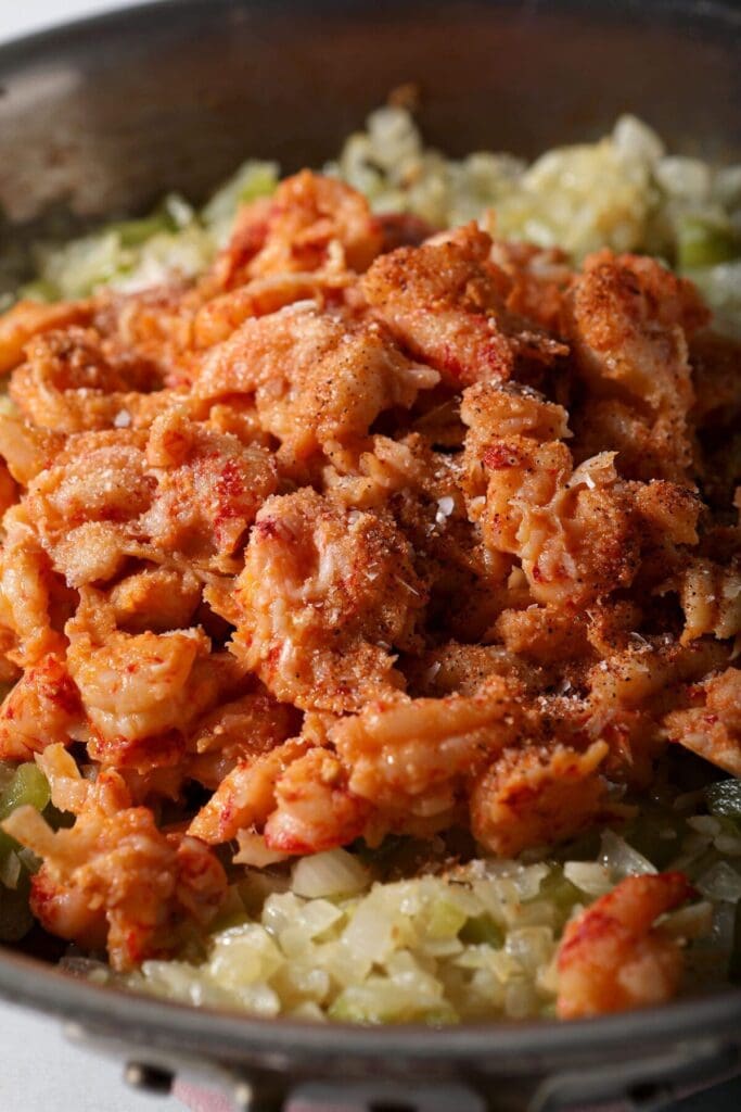 Crawfish tails on top of veggies in a pan