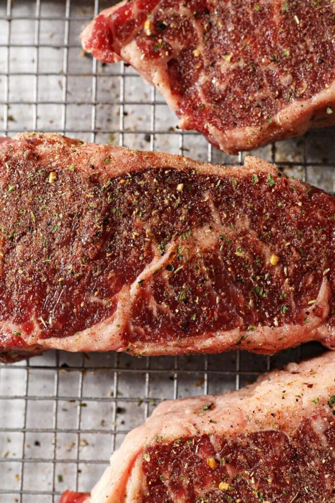 Steaks seasoned with a steak seasoning blend on a wire rack