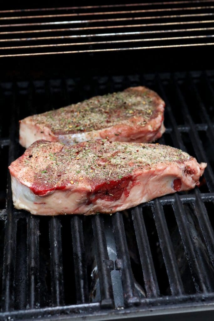 Two steaks on a grill seasoned with a homemade steak seasoning blend