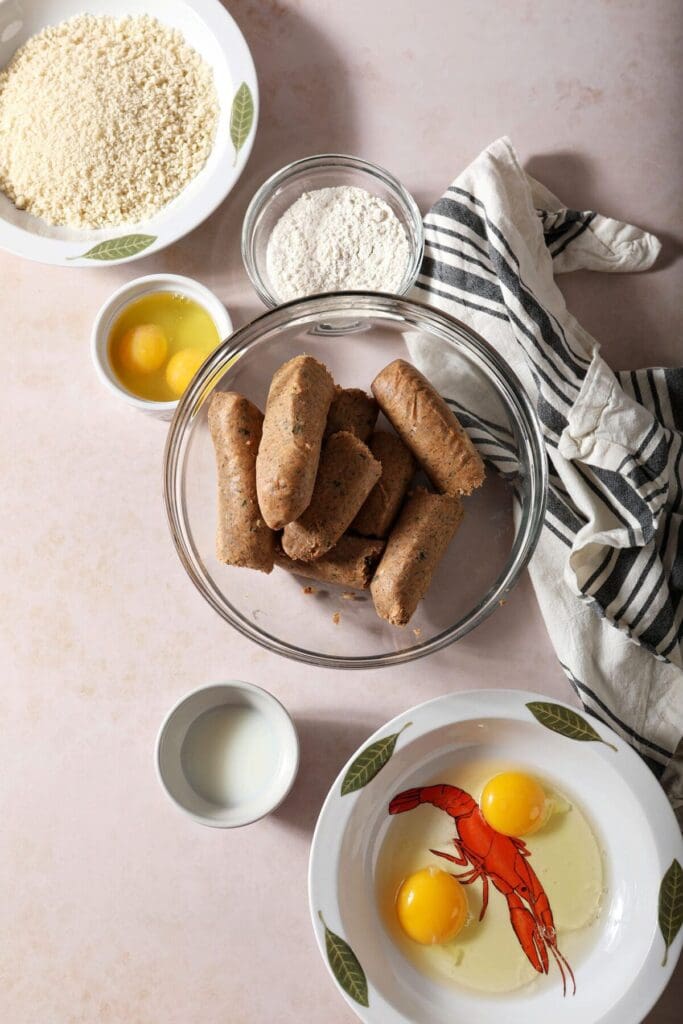 Ingredients to make baked boudin ball recipe in bowls on a light brown countertop