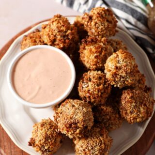 Baked boudin balls on a white plate with a dipping sauce