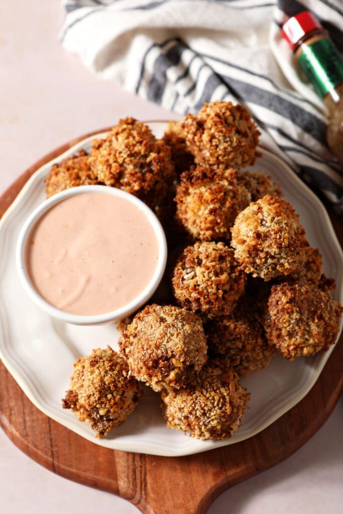 Baked boudin balls on a white plate with a dipping sauce