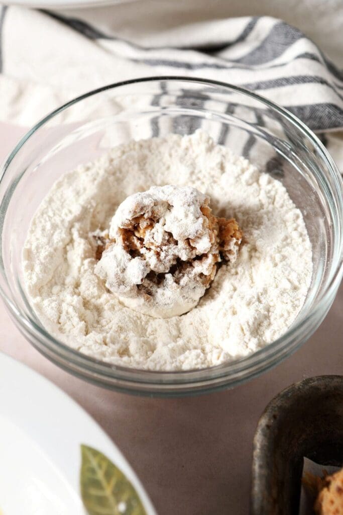 A boudin ball in a bowl of flour before it is breaded