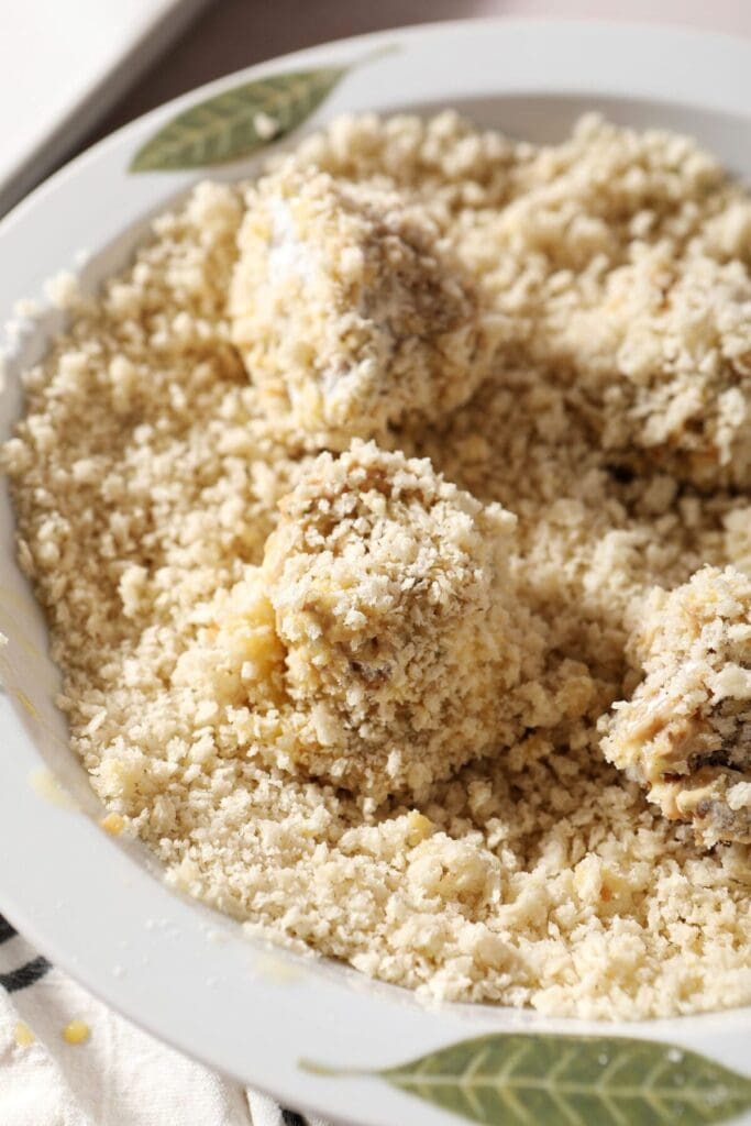 Close up of boudin balls in a bowl of panko bread crumbs