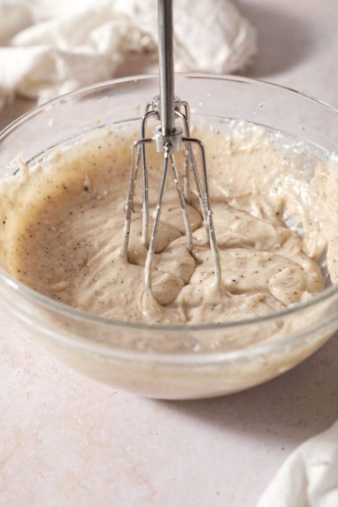 Completely blended brown butter frosting in a glass bowl with a hand mixer