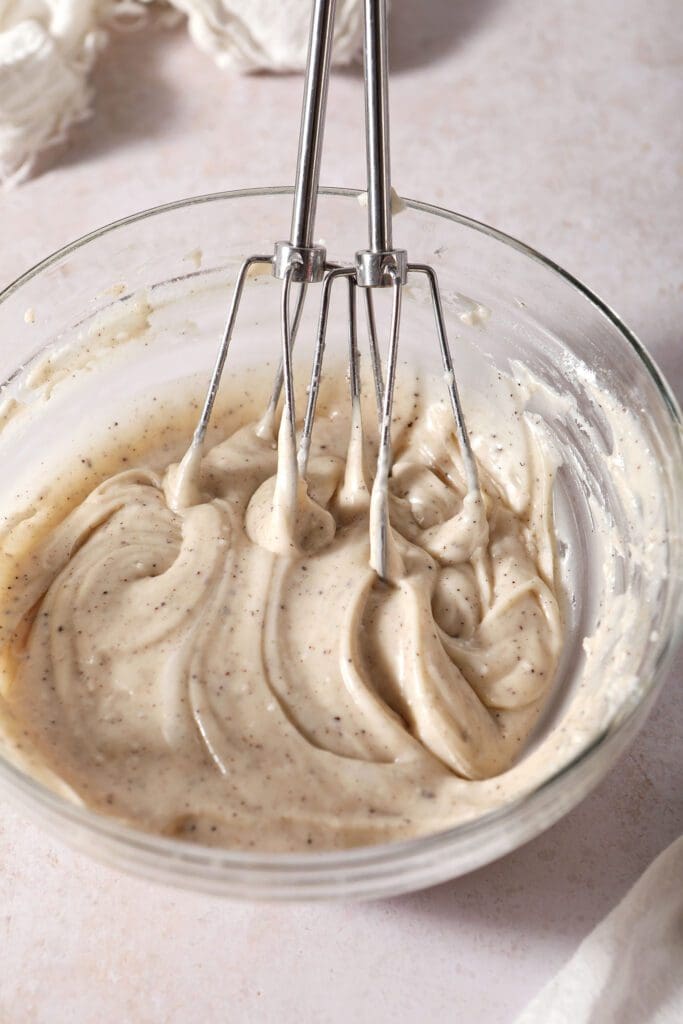 Hand mixer beaters in a bowl with blended brown butter frosting