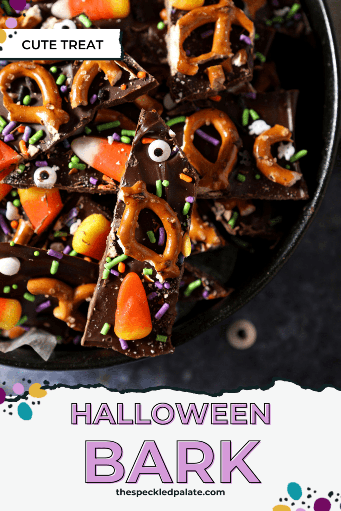 sliced halloween bark with candy eyeballs, pretzels, sprinkles and candy corn in a black bowl on a blue surface with the text halloween bark