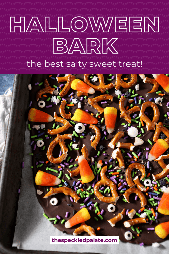 halloween bark on parchment on a sheet pan before slicing with the text halloween bark the best salty sweet trae