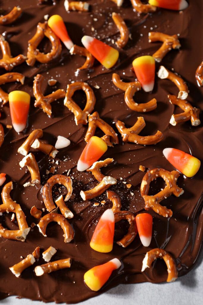 candy corn and chopped pretzels on top of melted chocolate bark